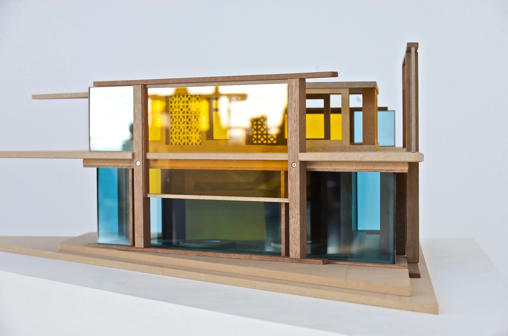 Architectural model of a house with a timber frame and coloured acrylic panels on a white background