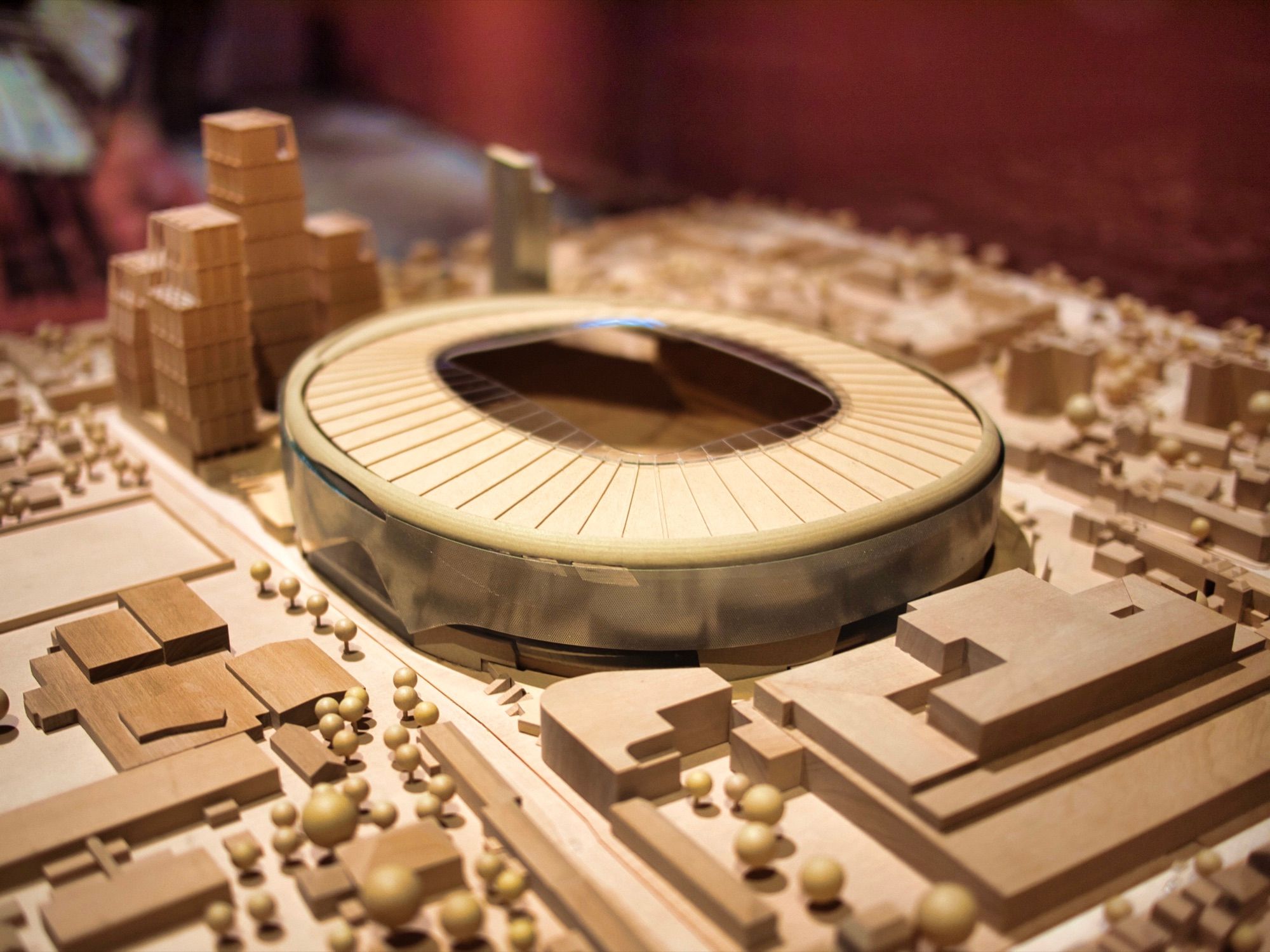Wooden architectural model of a stadium and its surrounding urban blocks, with scale buildings and trees