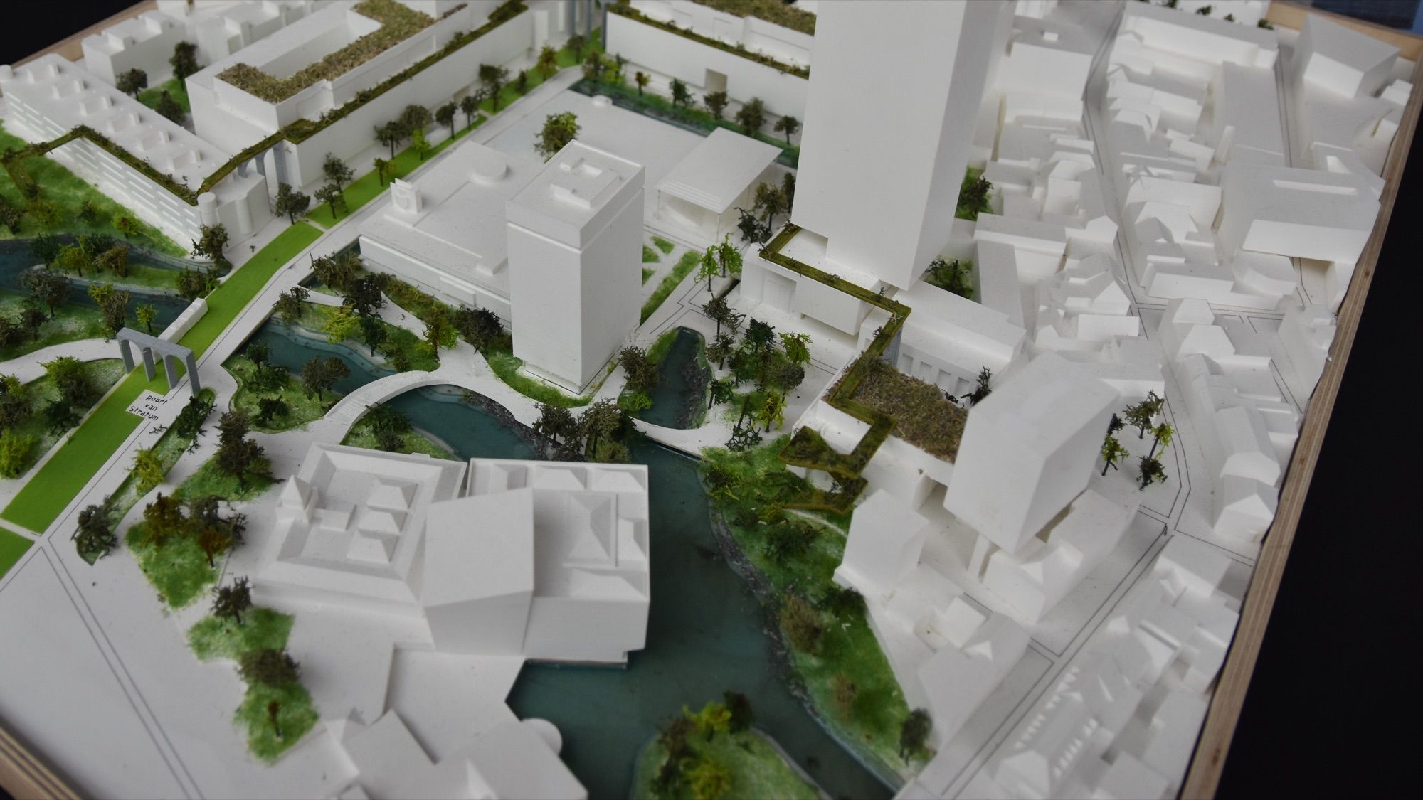 White architectural scale model of an urban masterplan with towers, green spaces, trees and a canal