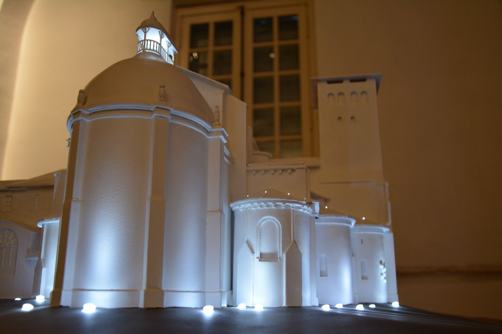 White interactive scale model of a Romanesque abbey lit by LED points set into its base