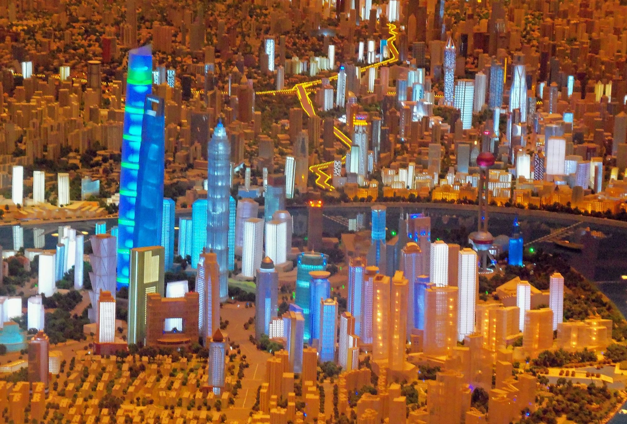 Scale model of Shanghai with skyscrapers lit from inside by blue and white LEDs beside the river